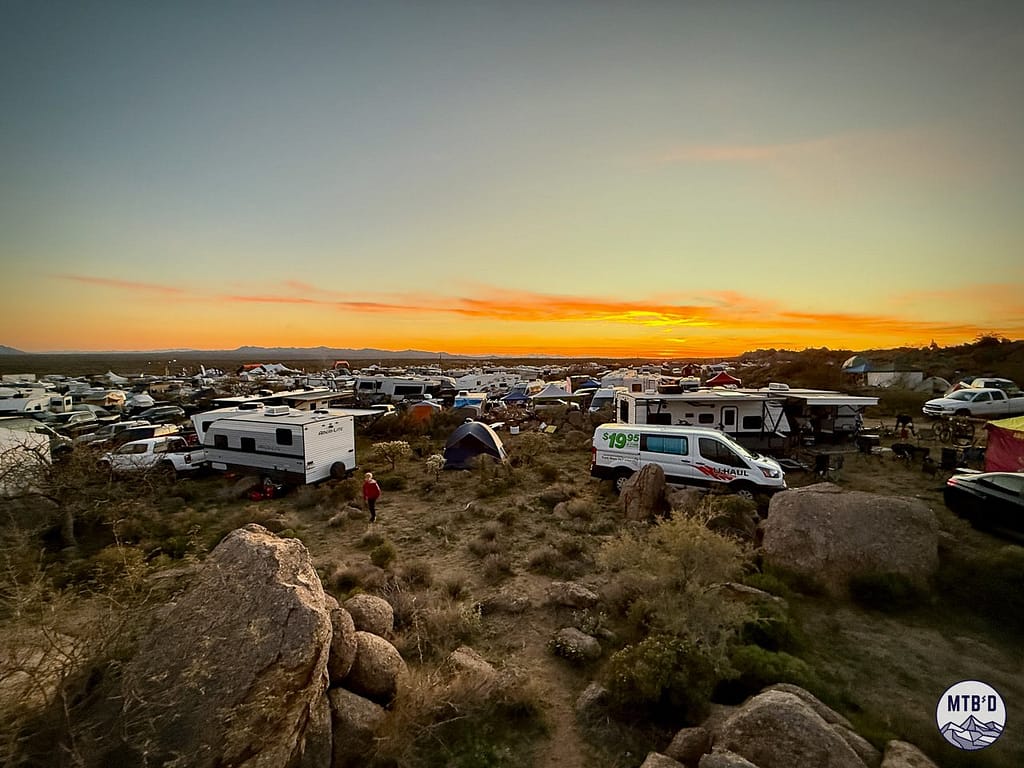 Sunset view over hundreds of campsites at 24 Hour Town during 24 Hours in the Old Pueblo north of Tucson, with riders still on course and an orange glowing sky to the west